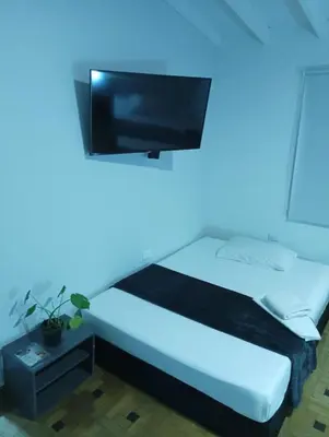 a bedroom with a bed with a tv on the wall at Hotel la Carpita in El Poblado
