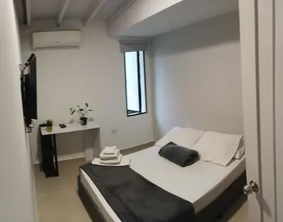 a small white room with a bed and a table at Hotel la Carpita in El Poblado