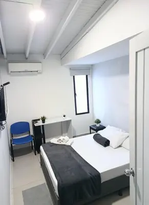 a bedroom with a bed and a desk with a blue chair at Hotel la Carpita in El Poblado