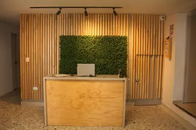 a green wall behind a desk with a laptop on it at Hotel la Carpita in El Poblado
