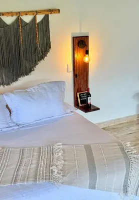 a bedroom with a bed with white sheets and a lamp at Cabañas Sentido Ancestral in Jardin