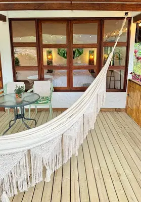 a hammock on a porch with a table and chairs at Cabañas Sentido Ancestral in Jardin