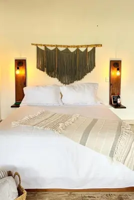 a bedroom with a large white bed with two windows at Cabañas Sentido Ancestral in Jardin