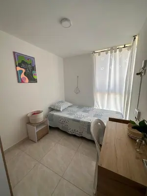 a small bedroom with a bed and a table at Acogedor Apartamento Como en casa in Manizales
