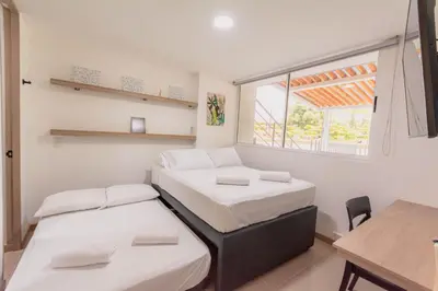 two beds in a room with a table and a window at Apartasol Dominica Citadela Di Sole in Santa Fe de Antioquia