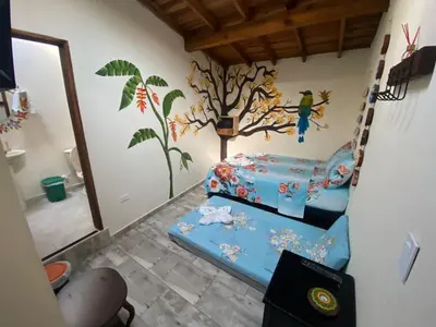 a bedroom with two beds and a tree mural on the wall at Hotel La Sultana in Jardin