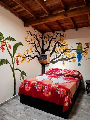 a bedroom with a bed with a tree mural on the wall at Hotel La Sultana in Jardin