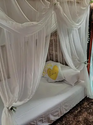 a bed with white curtains and a heart pillow at Finca Alto Bonito in Doradal