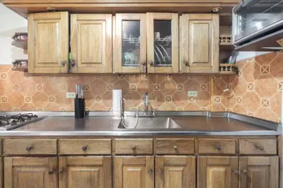 a kitchen with wooden cabinets and a stainless steel sink at Letto Hostal in Rionegro