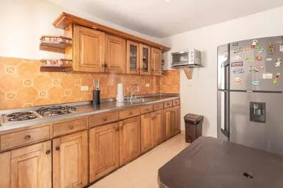 a kitchen with wooden cabinets and a stainless steel refrigerator at Letto Hostal in Rionegro