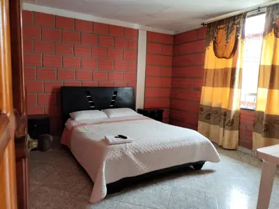 a bedroom with a bed and a red brick wall at Casa Hotel Los Faroles- Samaná/Caldas in Samaná