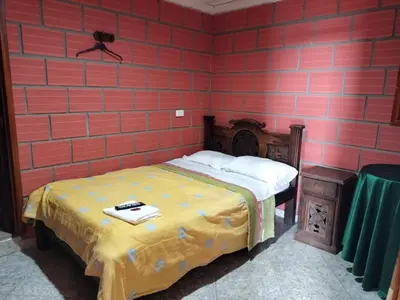 a bedroom with a bed and a red brick wall at Casa Hotel Los Faroles- Samaná/Caldas in Samaná