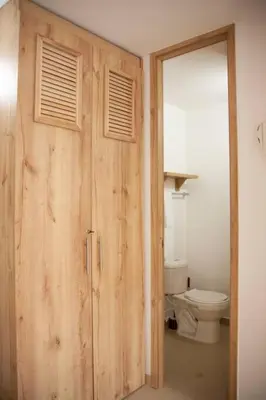 a bathroom with a wooden door leading to a toilet at Apartamento Duplex - Aqua Guatape in Guatapé