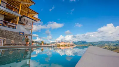 a swimming pool with a view of a house and mountains at Hotel Terra Belén in Belén de Umbría
