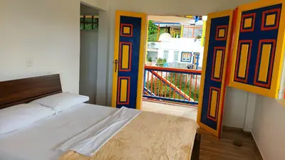 a bedroom with a bed and a door with a balcony at Hotel Terra Belén in Belén de Umbría