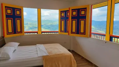 a bedroom with a bed and windows with mountains at Hotel Terra Belén in Belén de Umbría