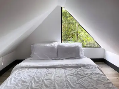 a bed in a room with a large window at Mini Casa en Poblado Medellín FRN109 By Roots Rentals in Medellín