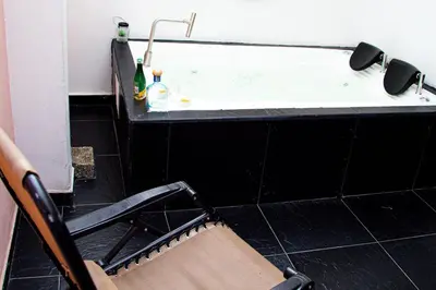 a bathroom with a bath tub with a chair and a sink at Casa Jiwa In Provenza in Medellín