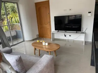 a living room with a table and a tv at Amplio y acogedor Apartamento Sabaneta. in Sabaneta