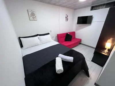 a bedroom with a black and white bed and a red chair at Edificio SantaMarta Medellín in Medellín