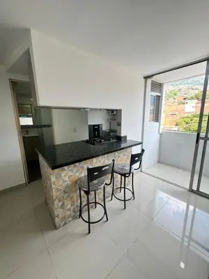 a kitchen with a bar with chairs and a counter top at Amplio ApartaStudio en Boston in Medellín