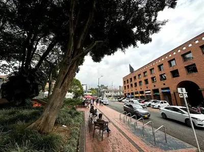 people sitting on benches on a sidewalk next to a street at ApartaStudio El Poblado in Medellín