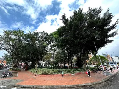 a park with trees and people walking on a street at ApartaStudio El Poblado in Medellín