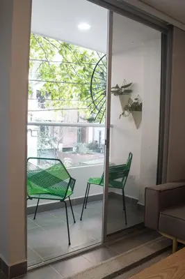 a glass door with a green chair in a living room at Espectacular apartaestudio en sabaneta! in Sabaneta