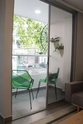 a glass door with a green chair in a living room at Espectacular apartaestudio en sabaneta! in Sabaneta