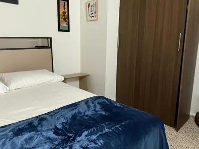 a bedroom with a bed and a wooden cabinet at Aparta Suite Torre De Prado 303 in Medellín