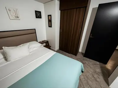a bedroom with a large white bed and a wooden door at Aparta Suite Torre De Prado 303 in Medellín