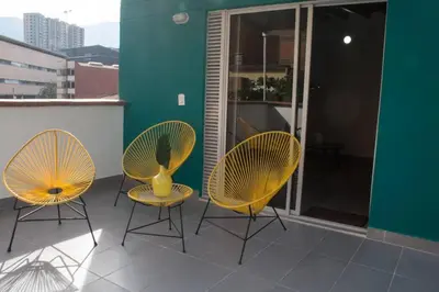 three chairs and a yellow vase on a balcony at Espectacular apartamento Duplex VIP 501 con jacuzzy in Sabaneta