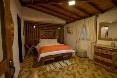 a bedroom with a large bed and a dresser at Jardin de los Silleteros Agro Parque Hotel in Santa Elena