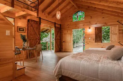 a bedroom in a wooden cabin with a bed and a table at Tominejo Ecolodge - Casas en los árboles in Neira