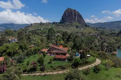 a house on a hill with a mountain in the background at Finca El paraíso Guatape in Guatapé