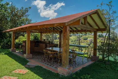 a wooden gazebo with a table and chairs at Finca El paraíso Guatape in Guatapé