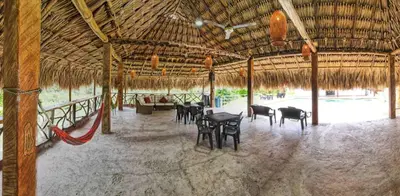 a room with chairs and tables and a straw roof at Parcela la cascada in Doradal
