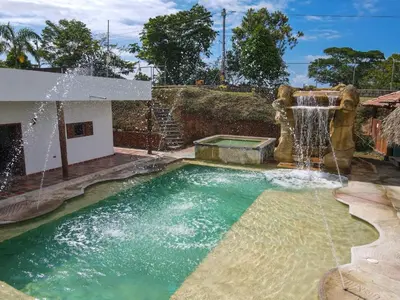 a swimming pool with a waterfall in a backyard at Parcela la cascada in Doradal