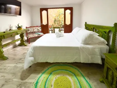 a bedroom with a large white bed and a rug at Paisa Territory Jardin in Jardin