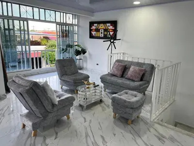 a living room with two chairs and a couch and a tv at Black and White Mariquita Tolima in Mariquita