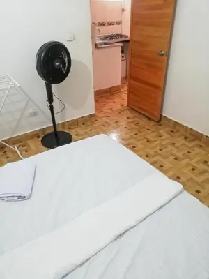 a room with a white bed and a black fan at Apartamento Barbie 3 in Mutatá