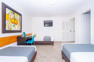 a room with two beds and a desk with a computer at HOTEL OASIS in Rionegro