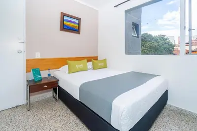 a bedroom with a bed with a desk and a window at HOTEL OASIS in Rionegro
