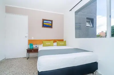 a white bedroom with a bed and a window at HOTEL OASIS in Rionegro