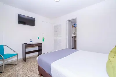 a bedroom with a bed and a desk and a chair at HOTEL OASIS in Rionegro
