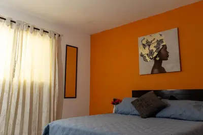 a bedroom with orange walls and a bed and a window at Hospedaje juandi in Medellín