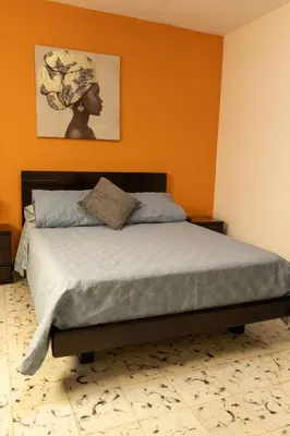 a bed in a bedroom with an orange wall at Hospedaje juandi in Medellín
