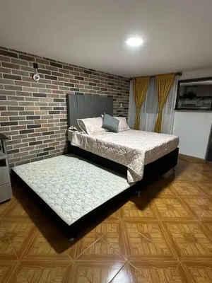 two beds in a room with a brick wall at Hospedaje juandi in Medellín
