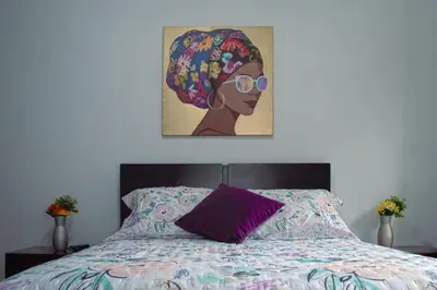 a bedroom with a bed with a painting of a woman at Hospedaje juandi in Medellín