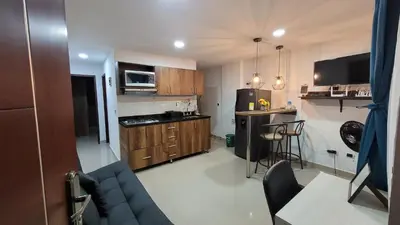 a small kitchen with wooden cabinets and a blue couch at ANDALIVING NIQUIA Apartaestudio in Bello